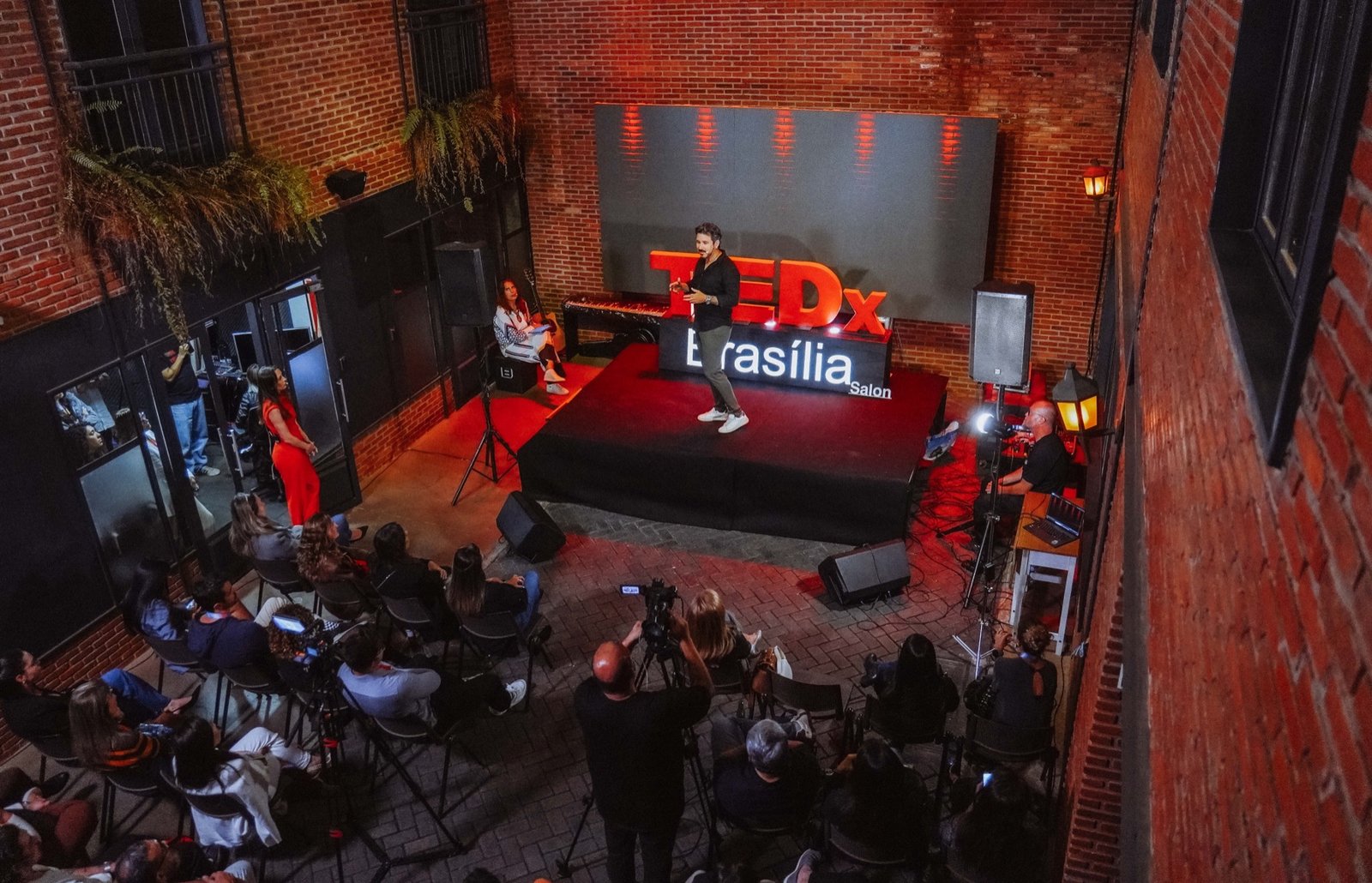 Dan Rocha discursando no palco vermelho e preto do TEDx Brasília